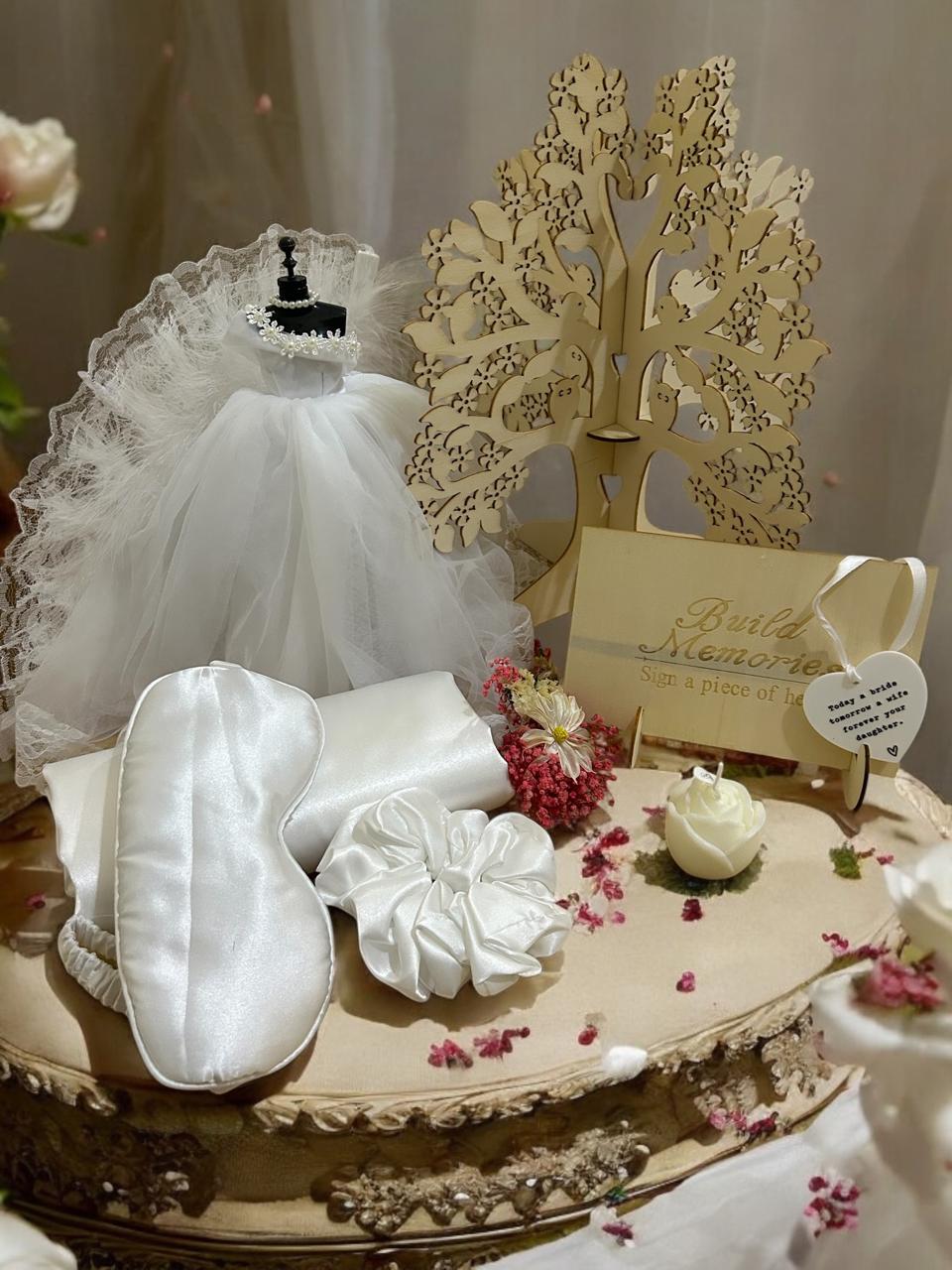 Elegifta Wedding Gift Set featuring an elegant mini wedding dress, sophisticated feather hand fan, beautiful guest book for memories, luxurious silk rose pillow cases, stylish hair tie, whimsical satan eye mask, serene white flower candle, meaningful wedding heart message, charming mini bouquet, and fragrant natural rose soap.